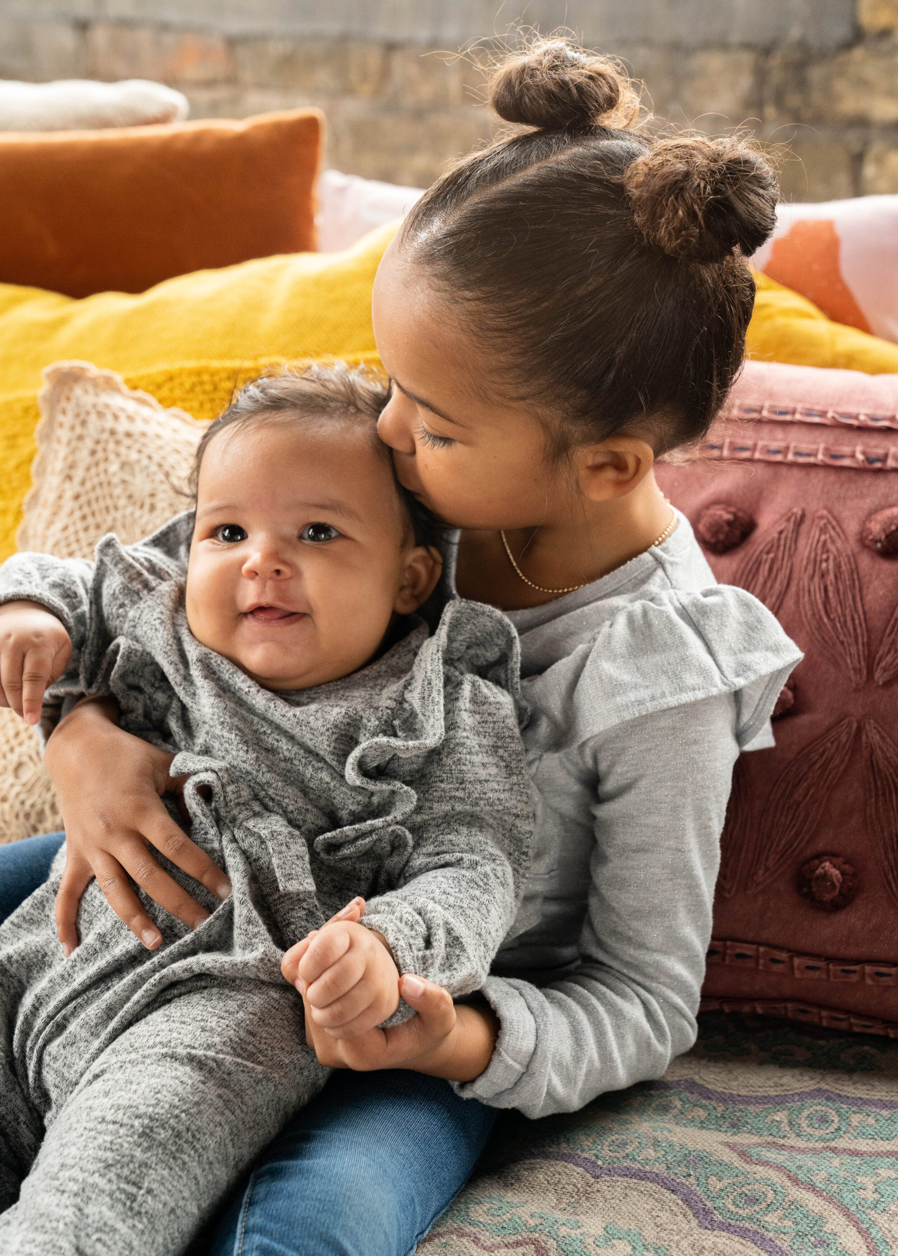 Big sister gives a kiss to her little sister - family session