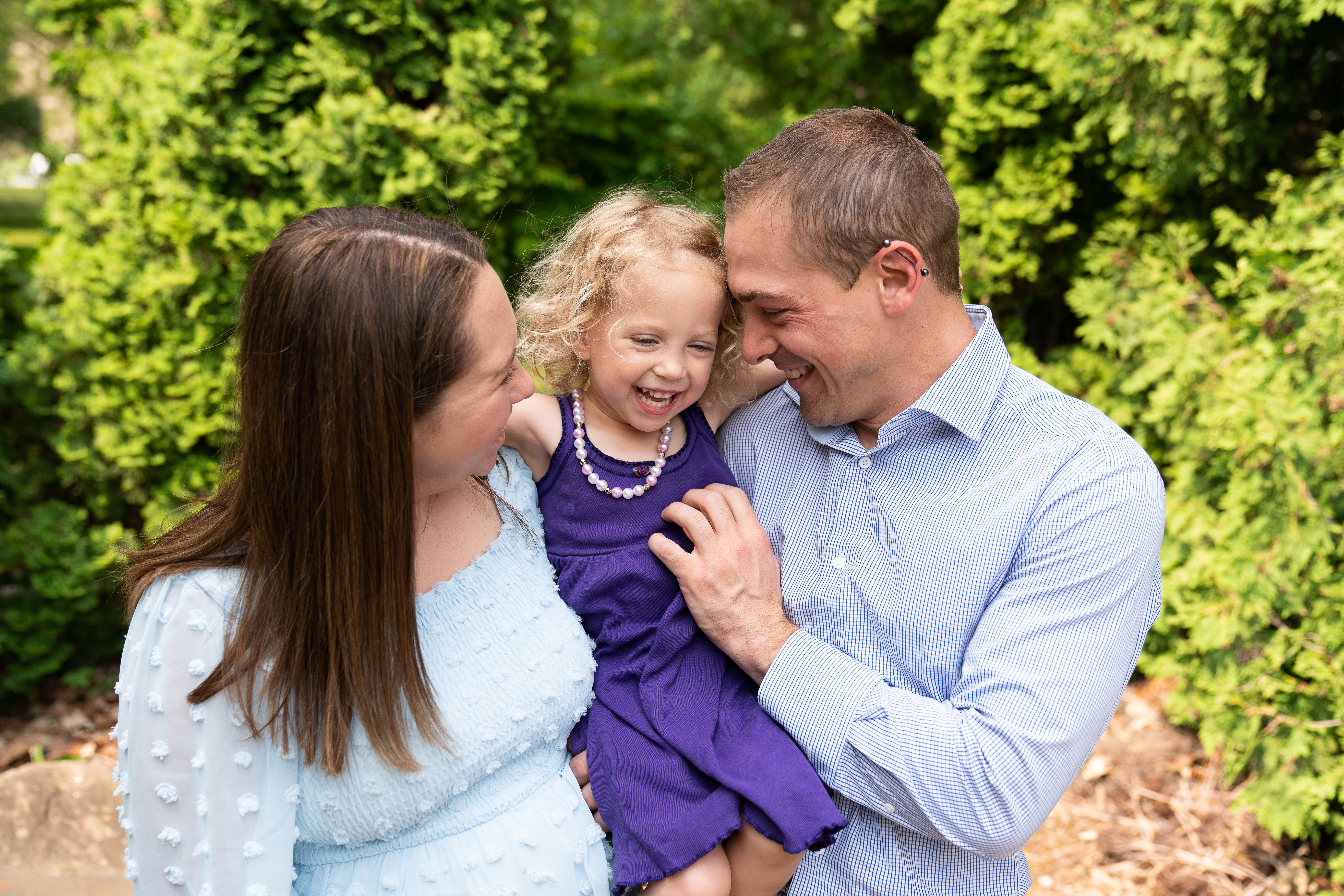 A mom and a dad tickle their little one during their family photoshoot at Arneson Acres Park in Edina, Minnesota.