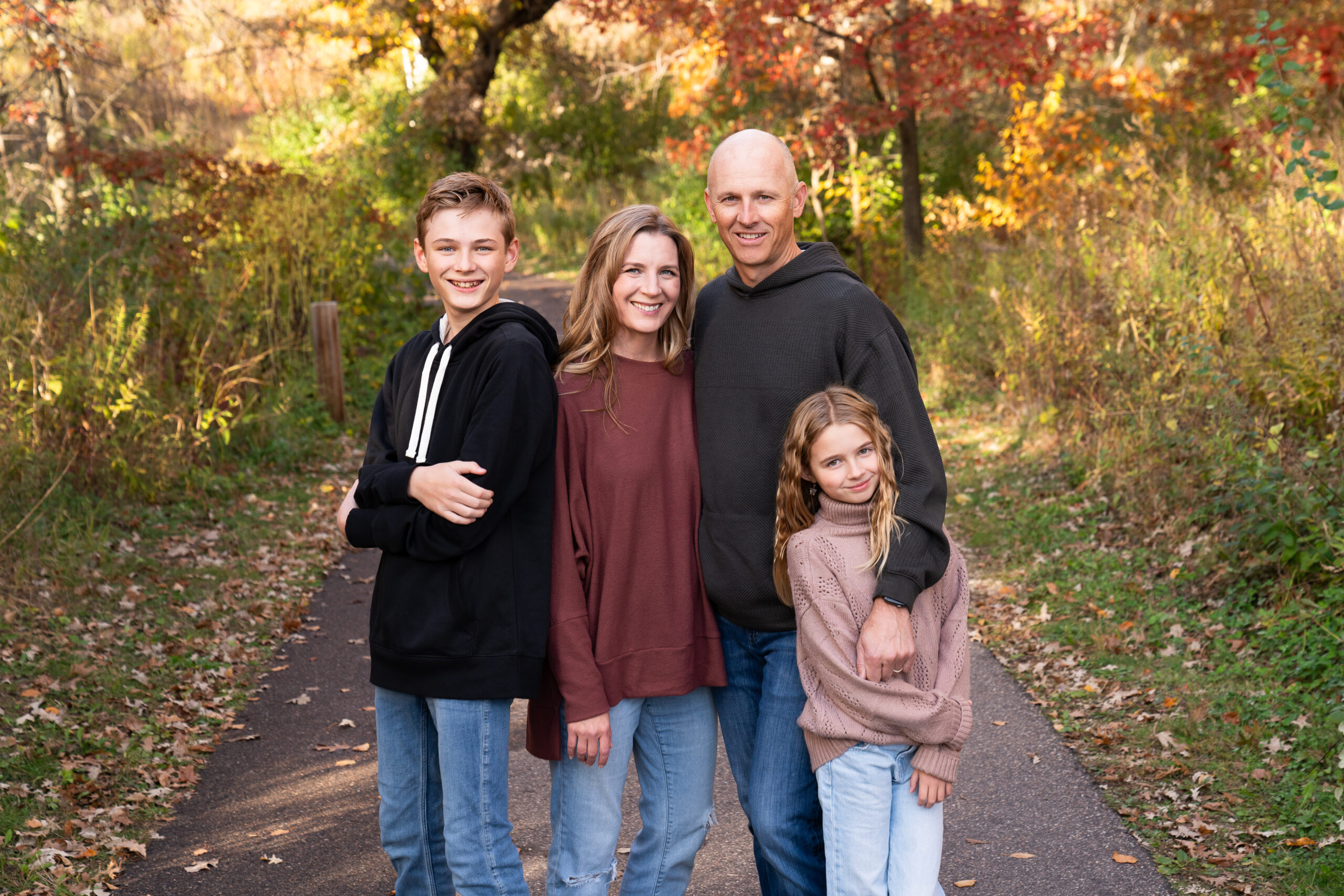Family of four poses together for their fall family photo at Lebanon Hills Regional Park in Eagan, Minnesota.