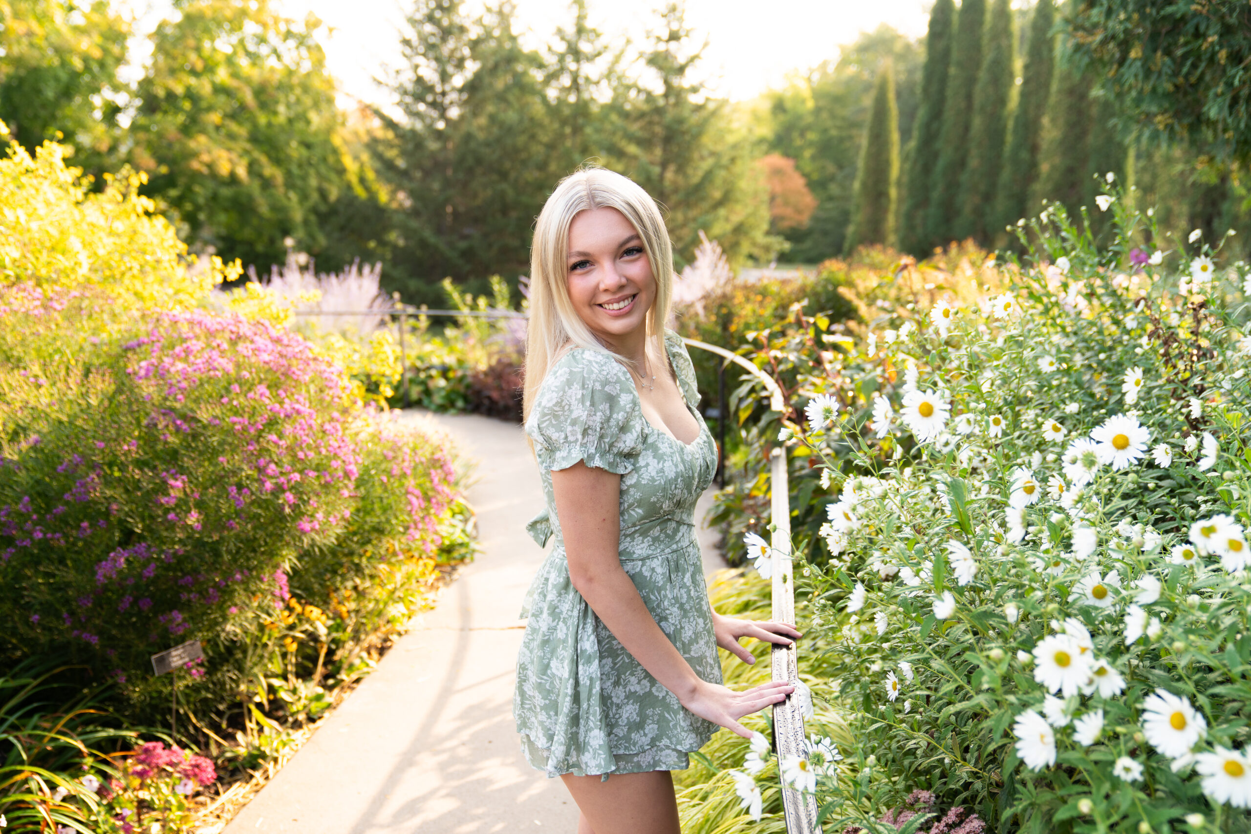 Teen girl poses in a flower garden for her senior photos at the Minnesota Landscape Arboretum in Chaska, Minnesota.