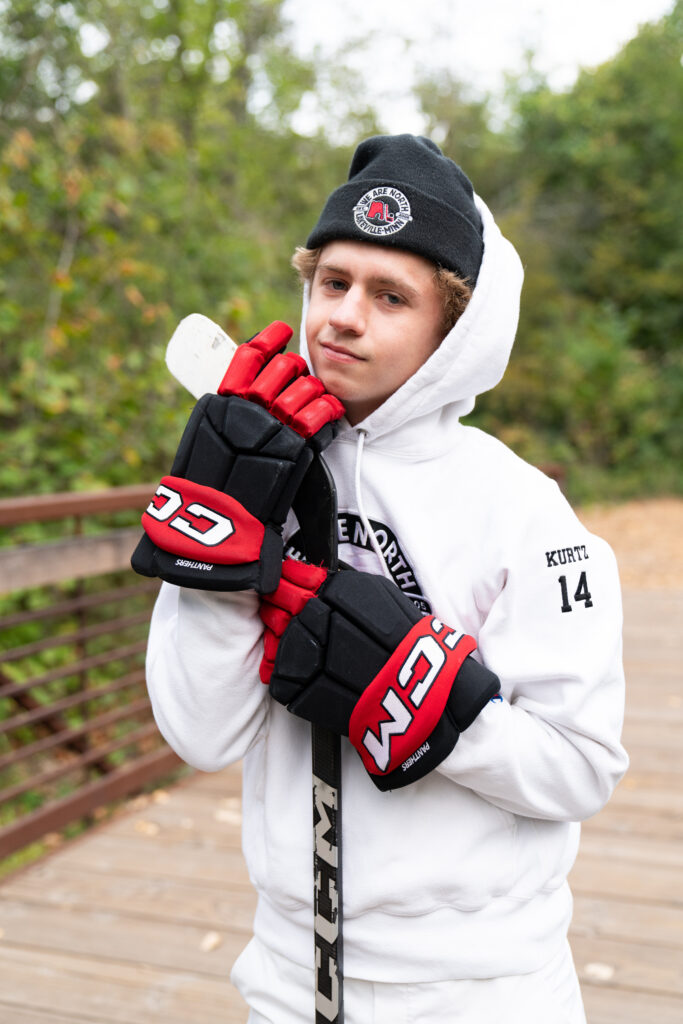 Hockey player poses with his hockey stick for his senior photos.