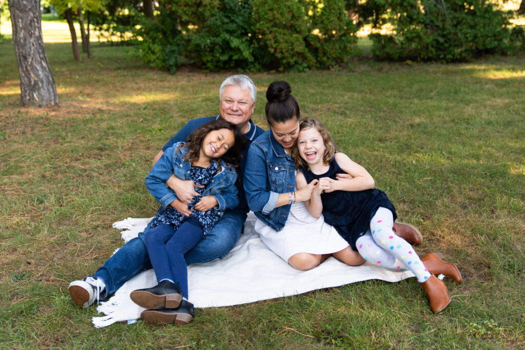 A mom and dad tickle their daughters during their summer family pictures.