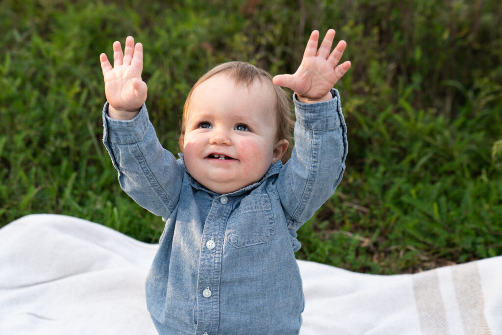 Toddler boy shows the camera how big he is during his birthday photo shoot.