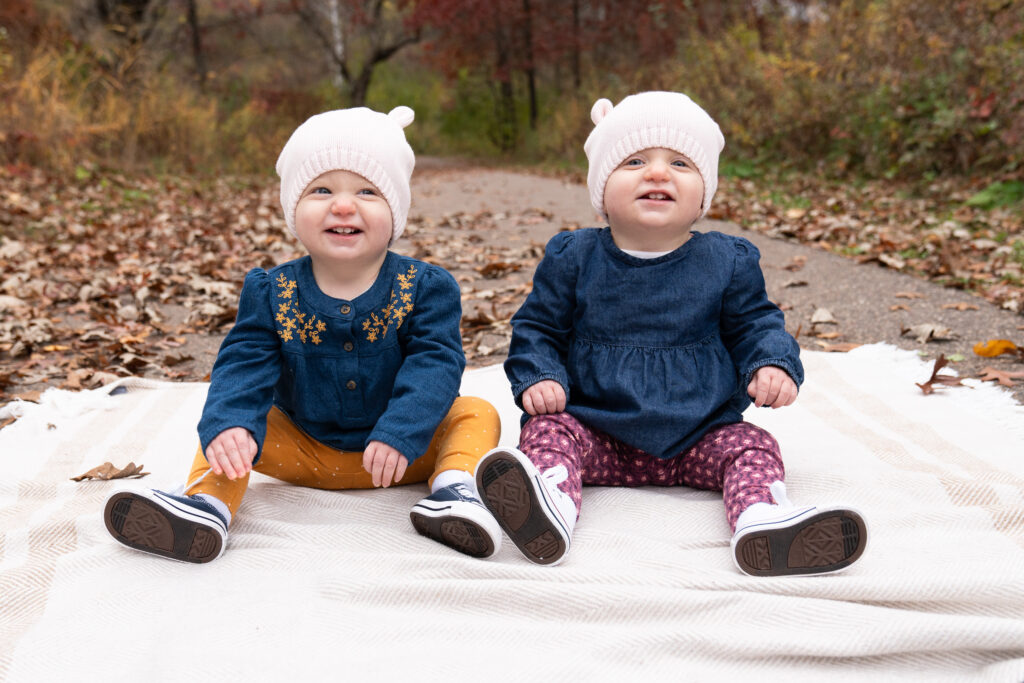 twin toddlers laugh at their parents behind the camera during their milestone session.