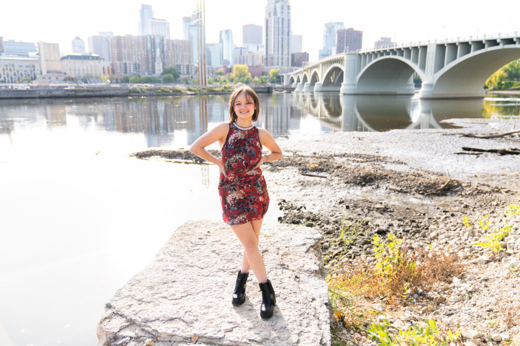 Girl poses on a rock that over looks a river in Minneapolis, Minnesota during her senior session.