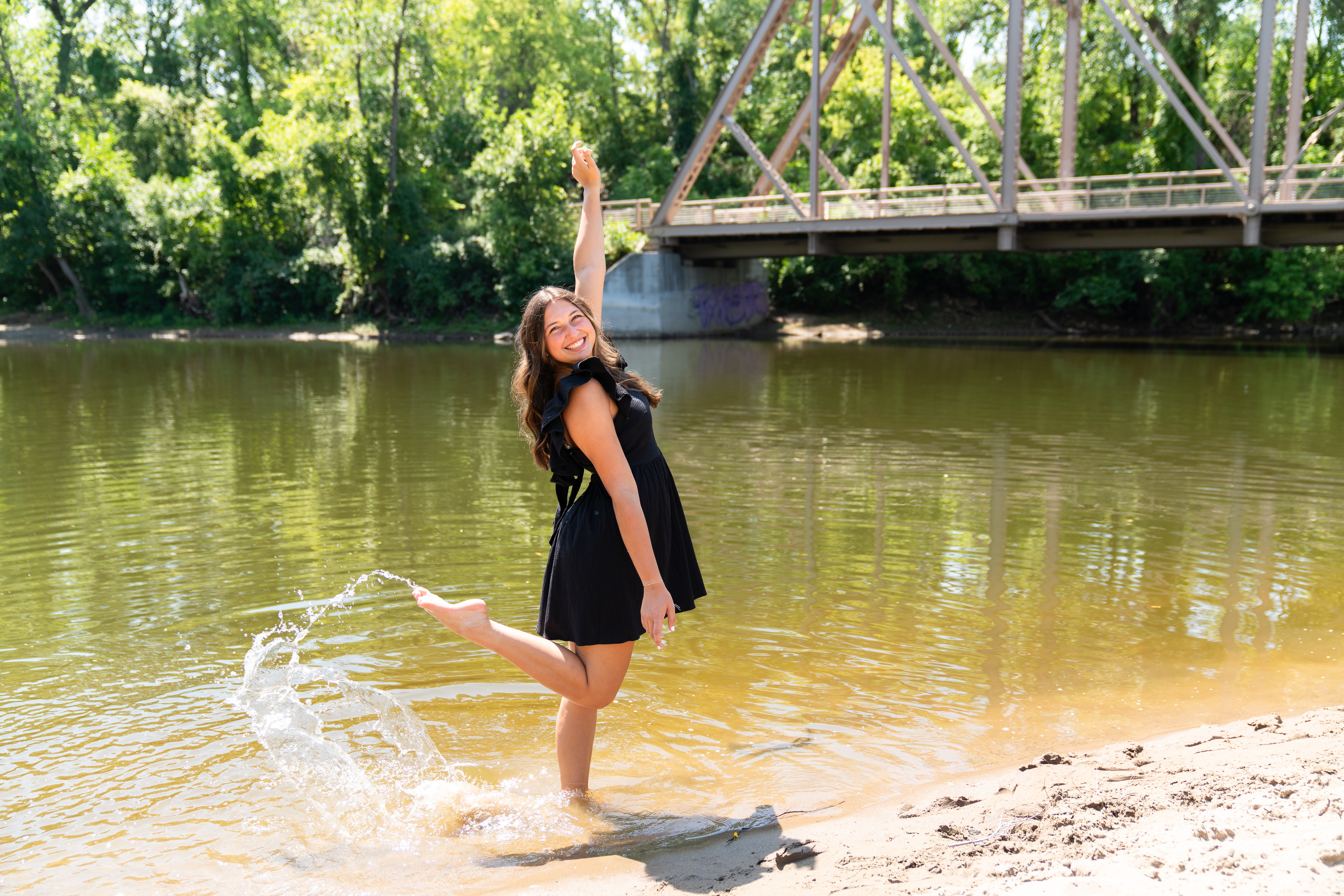 Senior girl plays in the water at Boom Island Park in Minneapolis during her senior photo shoot.