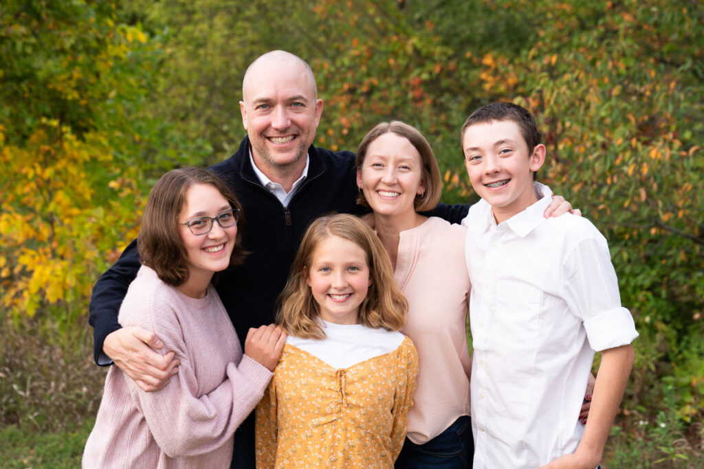 A family of five huddle together during their fall family portraits at Lebanon Hills Regional Park in Eagan, Minnesota.