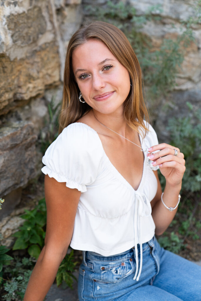 Senior girl plays with her necklace and looks at the camera during her senior pictures at the Mill City Ruins in Minneapolis, Minnesota.