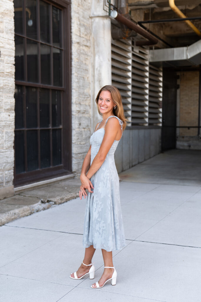 A teen girl wearing a light gray dress poses for her senior pictures.