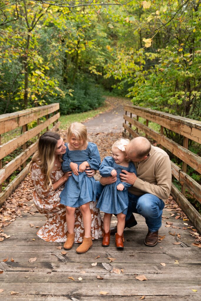 A mom and dad tickle their two daughters during their fall family photo shoot.