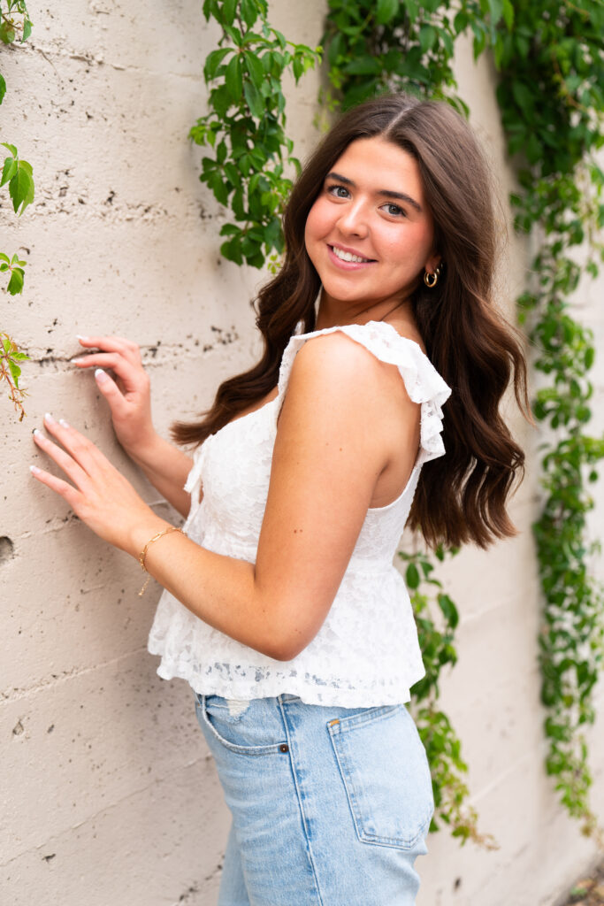 Girl poses next to an ivy wall for her senior pictures in downtown Minneapolis, Minnesota.