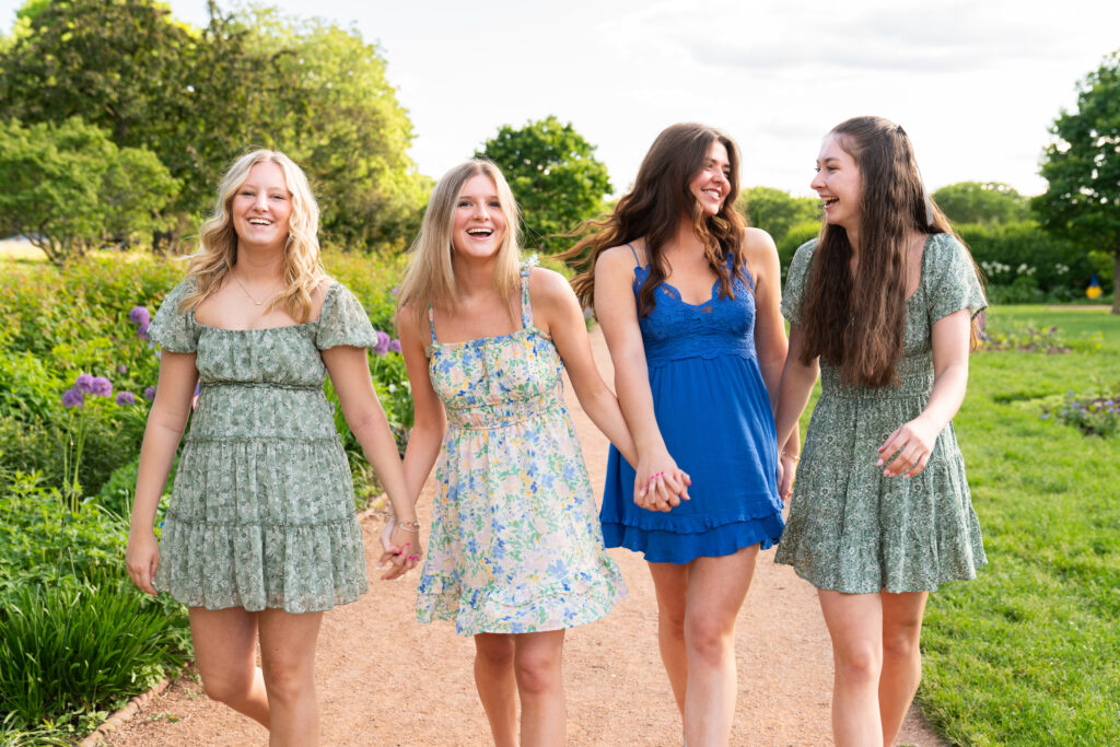 Four teen girls looking at each other laughing while they walk towards the camera during their spring senior rep photo shoot.